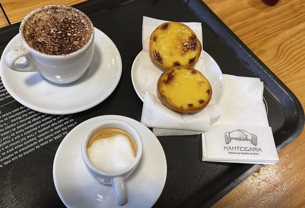 Pastel de nata recién horneado acompañado por una bica portuguesa