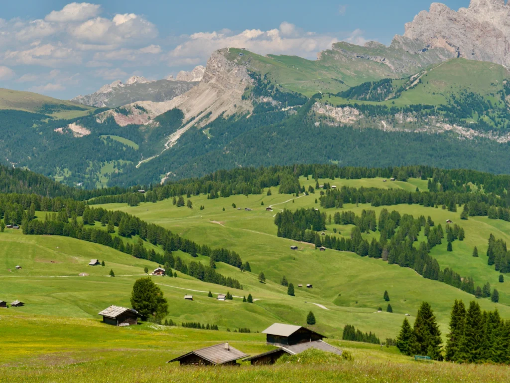 Prados de la Alpe di Siusi con cabañas de madera y el macizo del Sassolungo de fondo