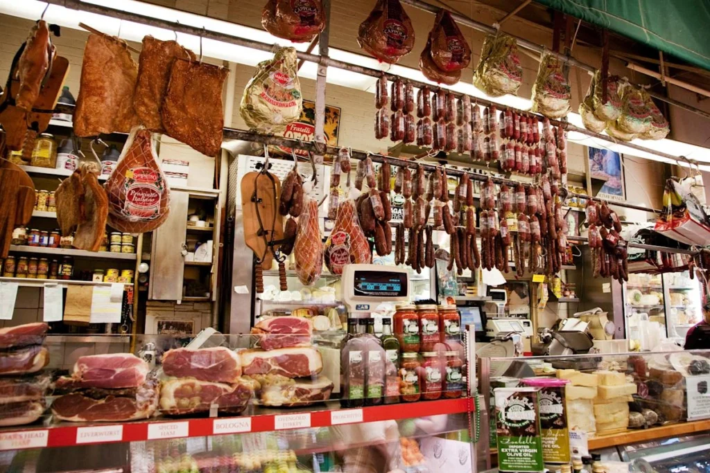 Mostrador de un deli italiano de Arthur Avenue en el Bronx con quesos y fiambres colgados