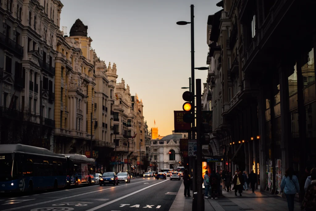 Calle del centro de Madrid al atardecer con gente caminando y balcones antiguos