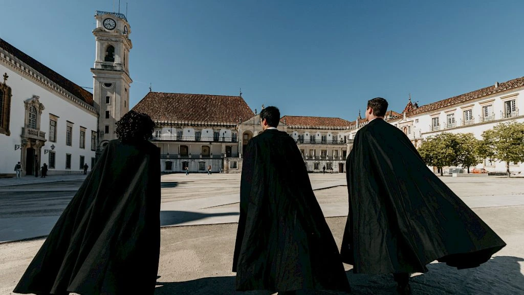 Estudiantes con capa negra caminando por las calles empedradas de la Alta de Coimbra