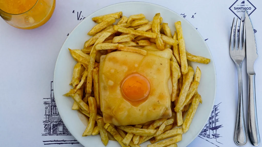 Francesinha bañada en salsa de tomate y cerveza con huevo y papas fritas en Oporto