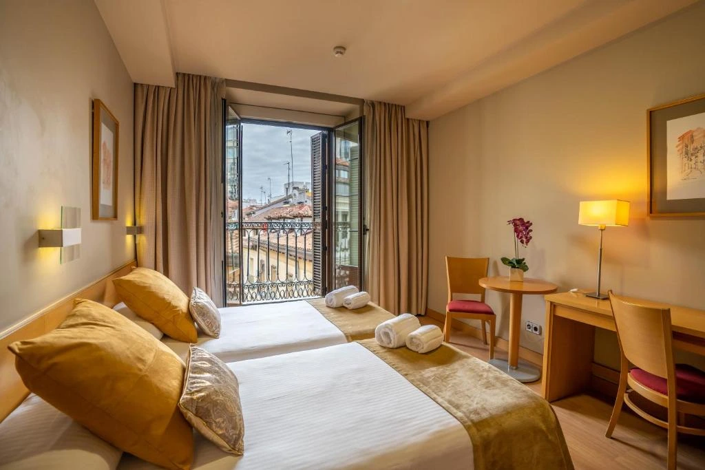 Habitación de hotel con balcón abierto sobre una calle del centro de Madrid