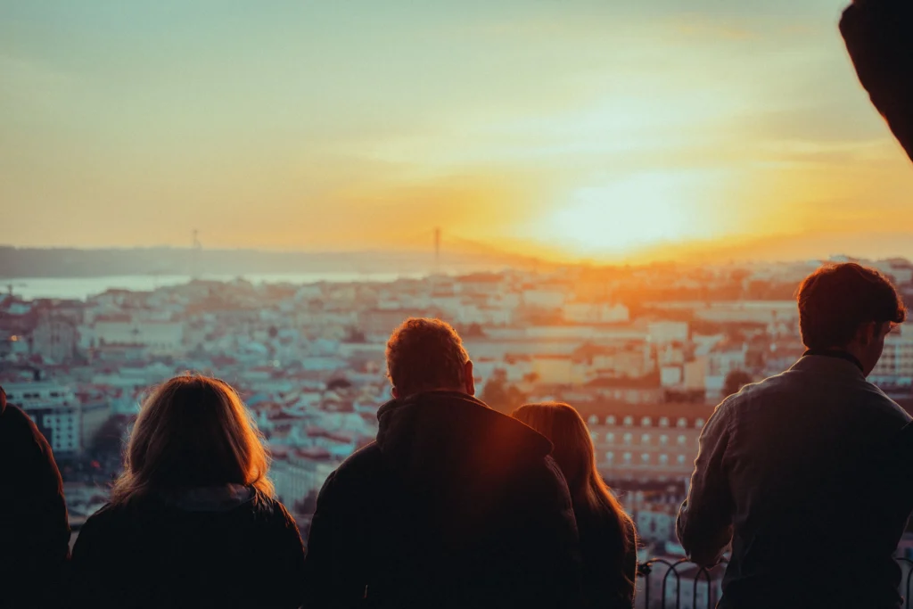 Personas en el mirador de Graça contemplando Lisboa al atardecer