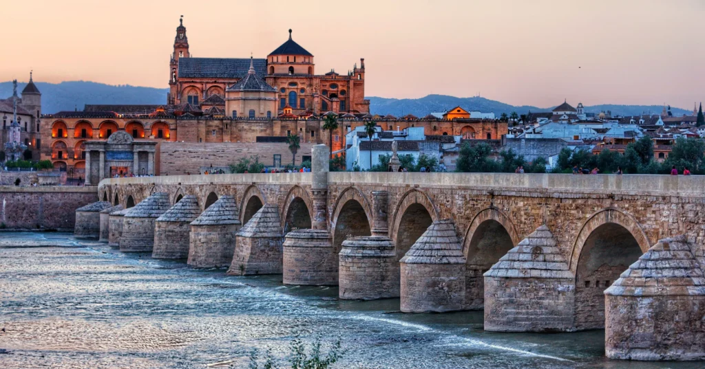 Puente Romano de Córdoba sobre el río Guadalquivir al atardecer con la Mezquita al fondo