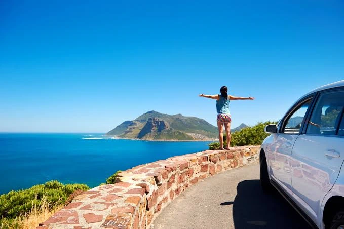 Ruta costera de Sicilia con vista al mar y un auto en la curva