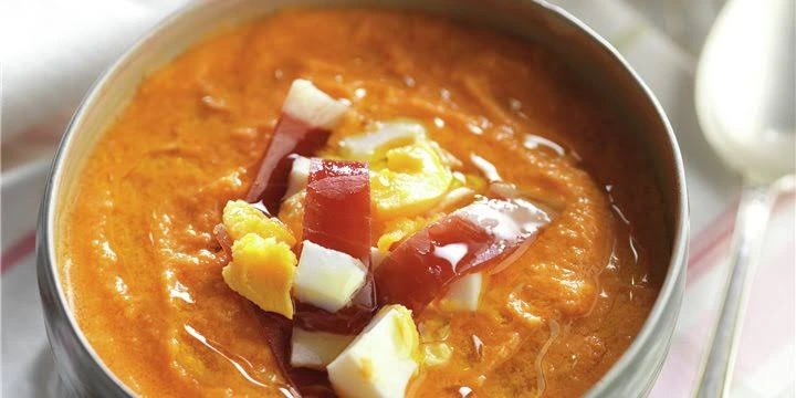 Plato de salmorejo cordobés con huevo duro y jamón en la mesa de un bar