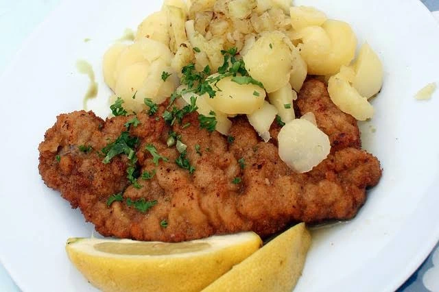 Plato de schnitzel vienés con limón y ensalada de papas en una mesa de restaurante