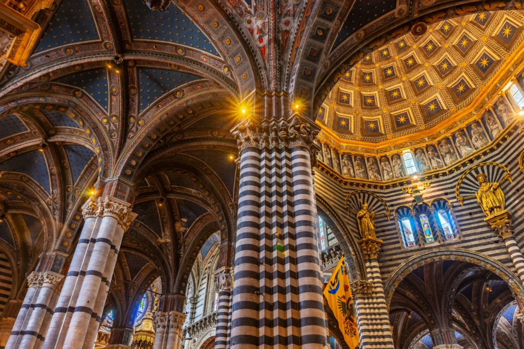 Interior del Duomo de Siena con columnas de mármol blanco y negro y su pavimento decorado