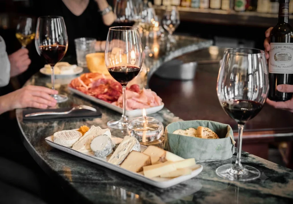 Tabla de quesos franceses con una copa de vino tinto en un bar de vinos de París