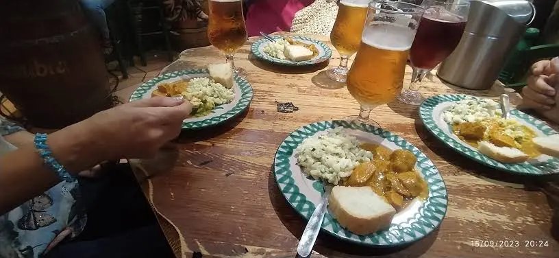 Caña de cerveza con una tapa servida en la barra de un bar de Granada